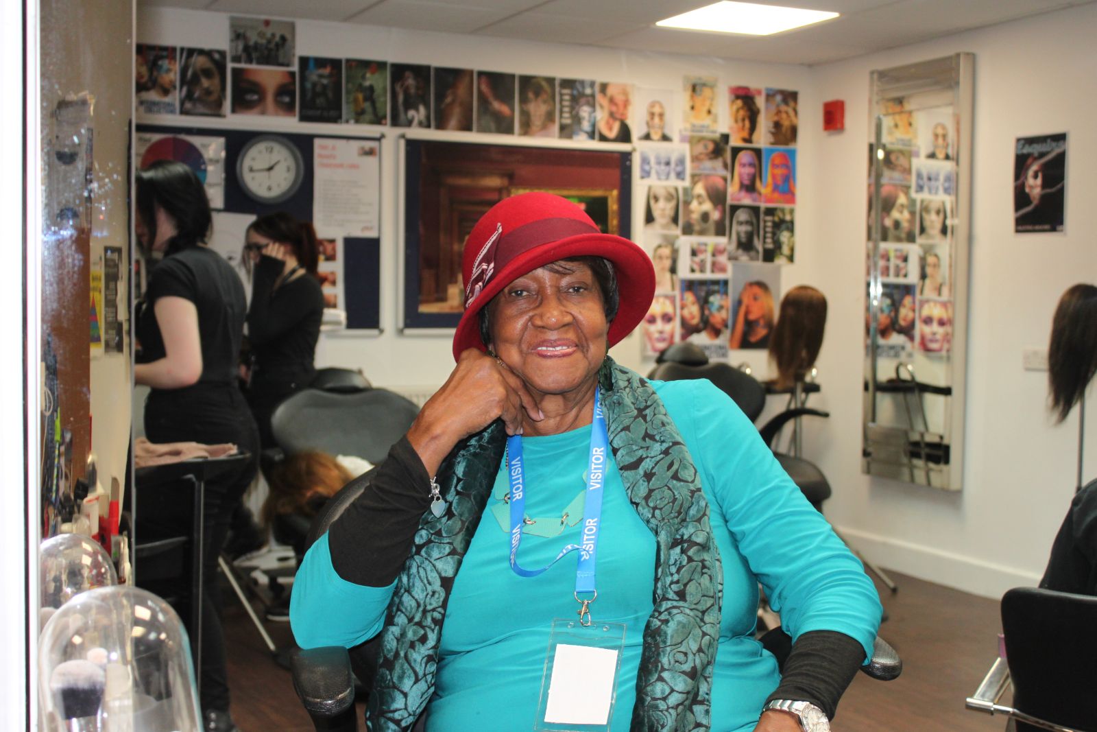 Lady sat smiling at the camera posing with a red hat on her head 